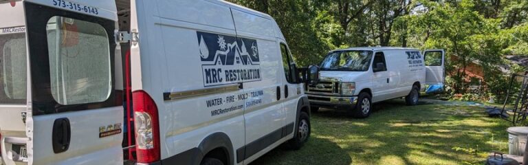 MRC Restoration vans parked on a residential lawn showcasing professional water fire mold and trauma restoration services