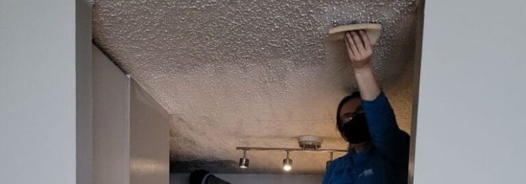 Professional cleaning technician scrubbing a soot stained ceiling during wall and ceiling cleaning services for smoke damage restoration by MRC Restoration