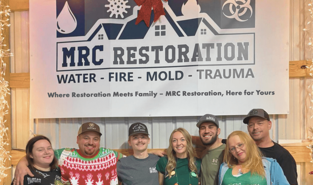 MRC Restoration team and their families standing under the company sign symbolizing their family oriented values and commitment to restoration services