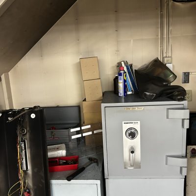 Fire-damaged safe and storage area with soot-covered walls and equipment.