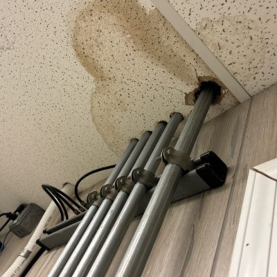 Severe roof leak water damage creating a hole in the ceiling of a commercial building.