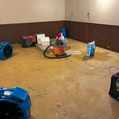 Basement undergoing water damage restoration with drying equipment.