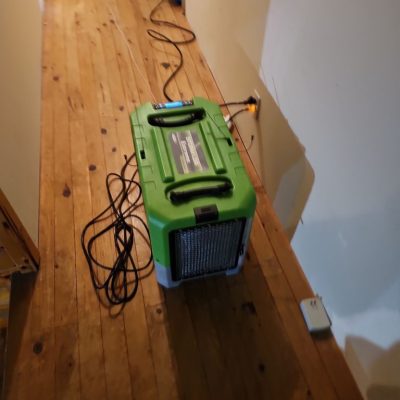 Dehumidifier working in a hallway with wooden floors to remove moisture and dehumidify the space.