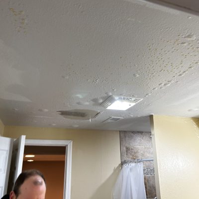 Ceiling damage with water stains and bubbling paint in a flooded area.