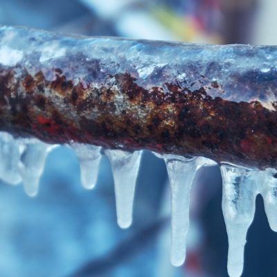 Frozen pipe covered in ice, highlighting the risk of burst pipes and water damage during winter.